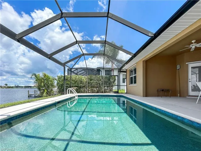 Swimming pool featuring a sunroom, a lanai, a ceiling fan, a water view, and a patio