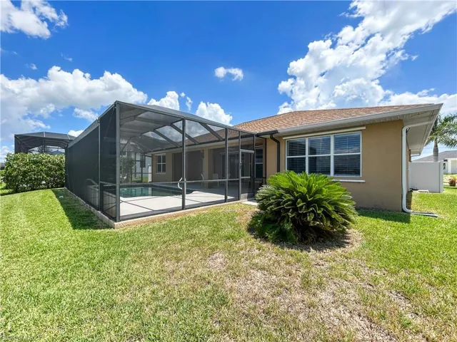 Back of house with glass enclosure, a sunroom, a yard, and an outdoor pool