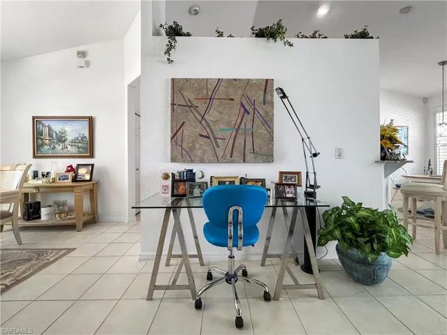 Office space with light tile patterned floors and vaulted ceiling