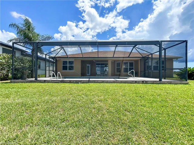 Back of house with a lanai, a yard, stucco siding, and a sunroom