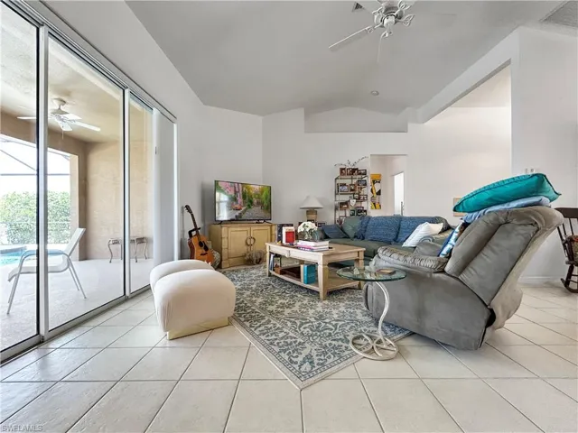 Living area with ceiling fan, light tile patterned floors, and lofted ceiling