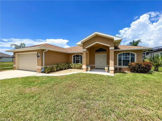 View of front of property featuring stucco siding, driveway, an attached garage, and a front lawn
