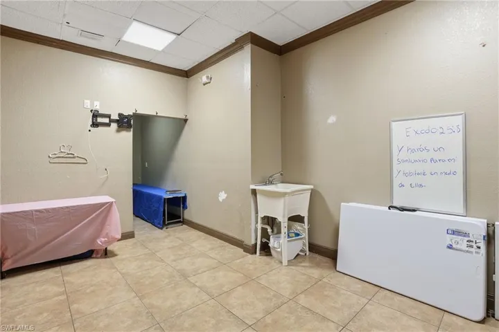 Laundry room featuring crown molding and a textured wall