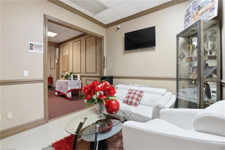 Carpeted living area featuring a paneled ceiling, tile patterned floors, and a textured wall