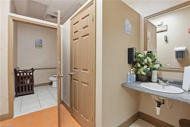 Bathroom featuring light tile patterned floors, a textured wall, and a paneled ceiling