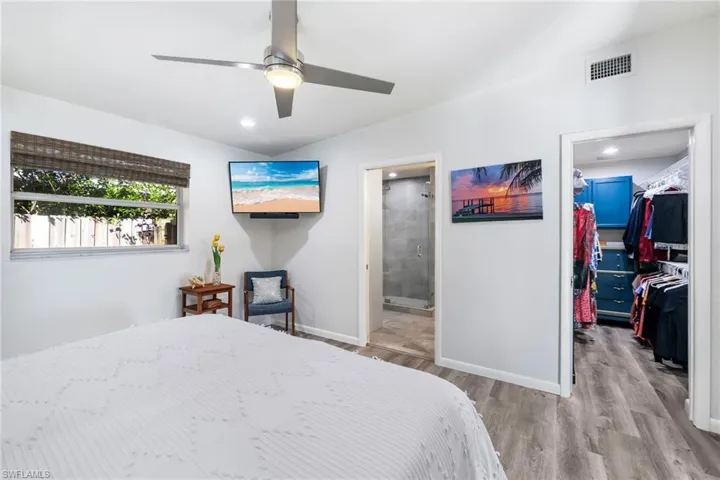Bedroom featuring a walk in closet, ensuite bath, ceiling fan, light hardwood / wood-style floors, and a closet