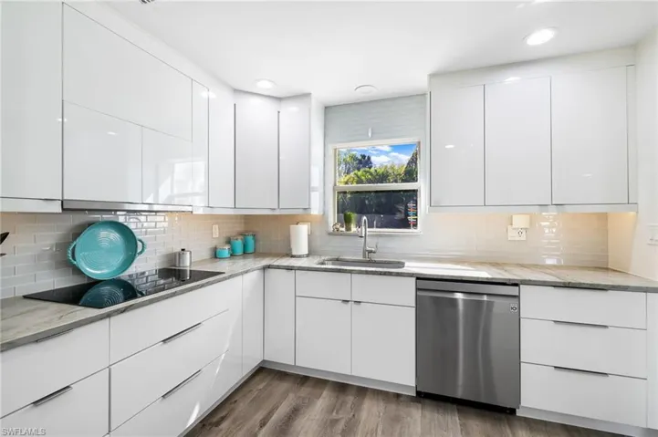 Kitchen featuring white cabinets, dishwasher, black electric stovetop, and sink