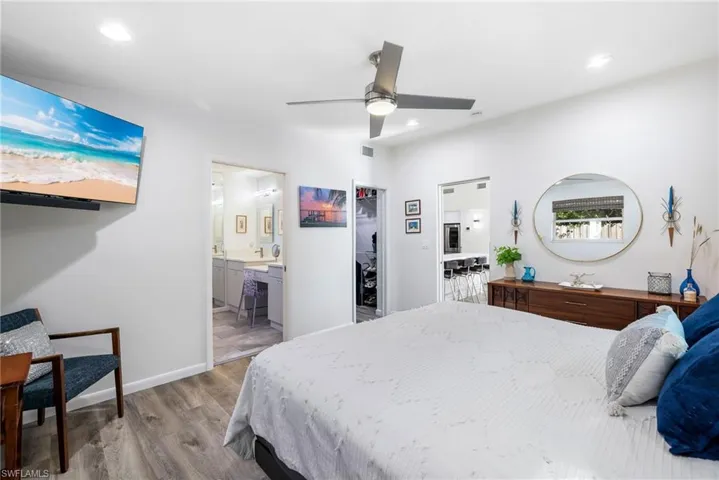 Bedroom with light wood-type flooring, a walk in closet, ceiling fan, connected bathroom, and a closet