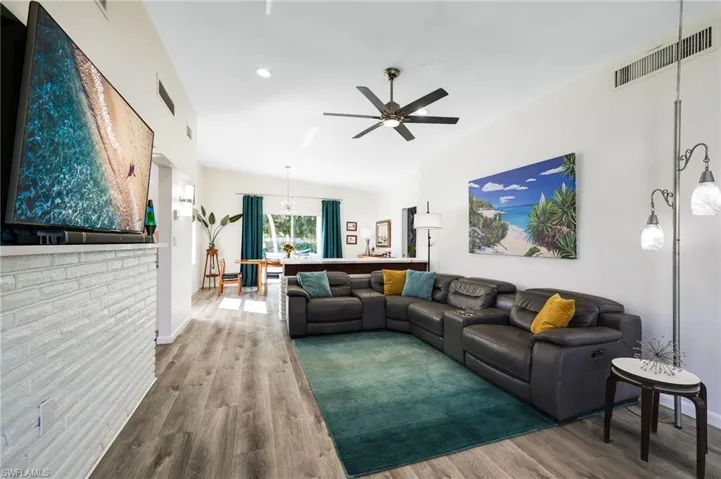 Living room with hardwood / wood-style flooring, ceiling fan, and vaulted ceiling