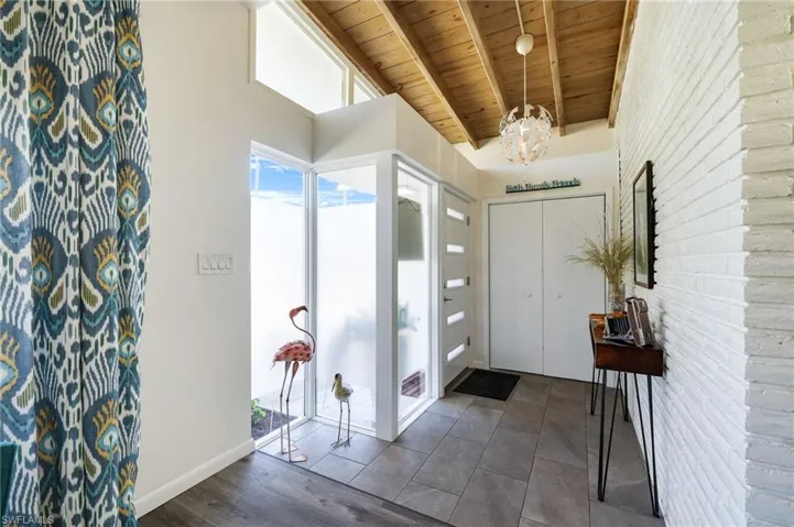 Entrance foyer featuring a chandelier, dark hardwood / wood-style flooring, beamed ceiling, and wood ceiling