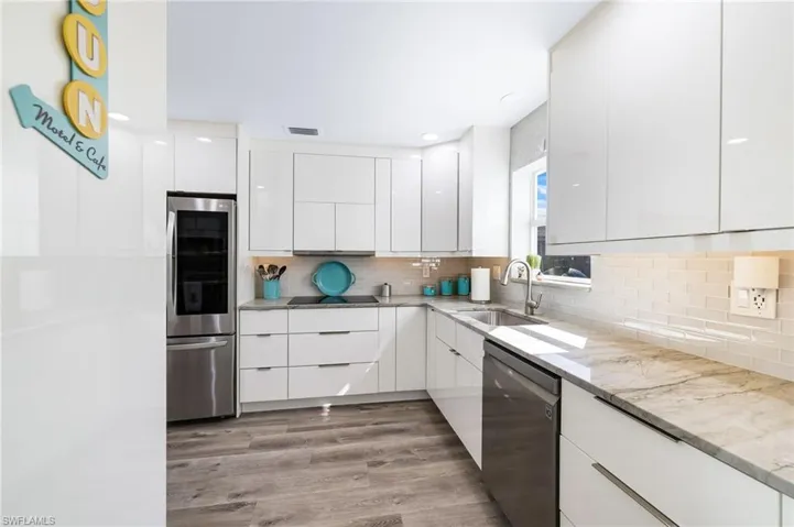 Kitchen featuring light stone countertops, white cabinets, light hardwood / wood-style floors, and appliances with stainless steel finishes