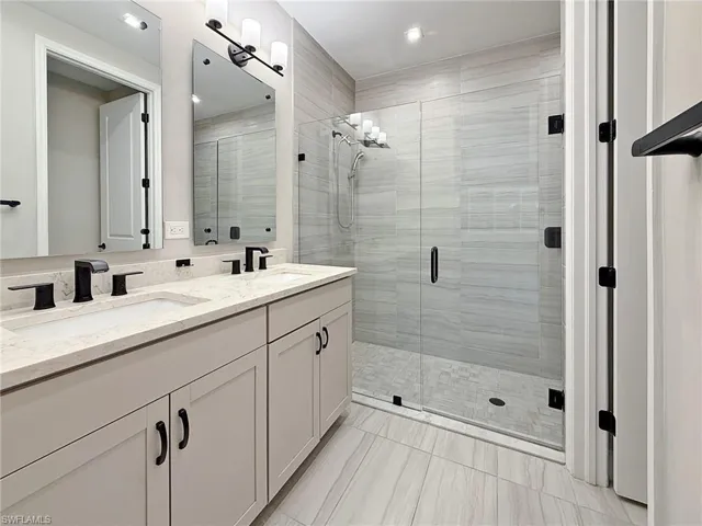 Full bathroom featuring double vanity, a shower stall, and recessed lighting