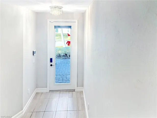 Doorway to outside with a chandelier and tile patterned floors