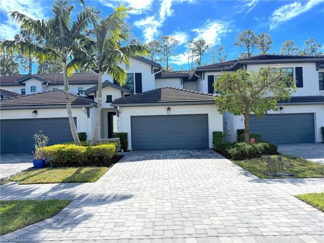 Traditional-style home with decorative driveway, stucco siding, and a tiled roof