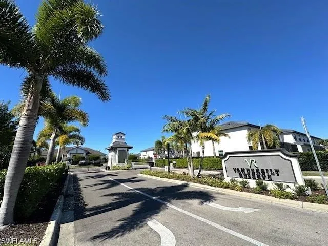 View of asphalt street featuring curbs and a gated entry