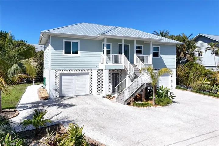 Beach home featuring a garage, driveway, covered porch, and a metal roof