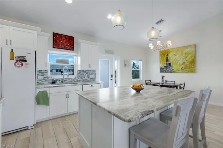 Kitchen with freestanding refrigerator, wood finish floors, white cabinets, and lofted ceiling