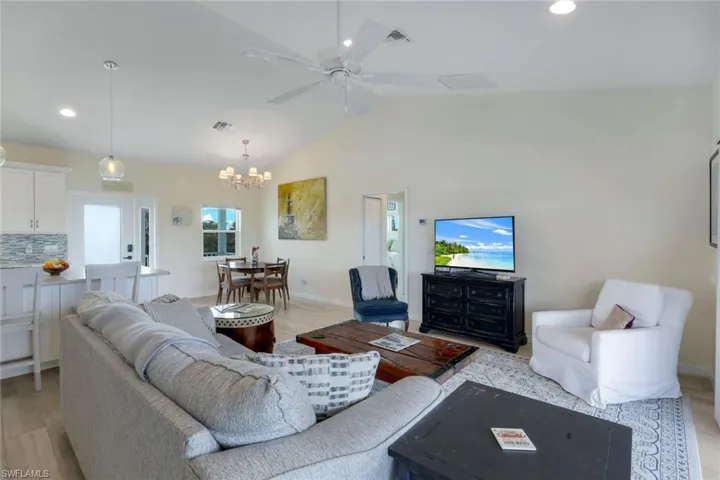 Living room featuring suspended lighting, a ceiling fan, light wood-type flooring, and lofted ceiling