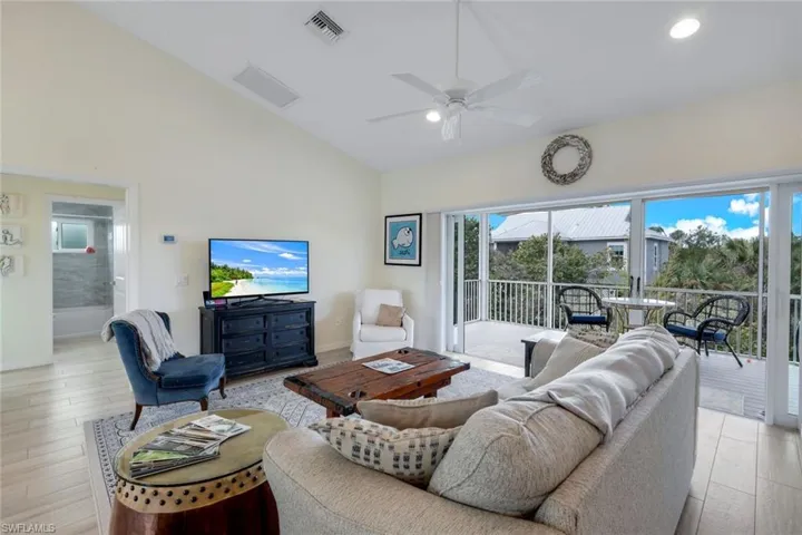 Living room featuring lofted ceiling, a ceiling fan, light wood finished floors, and healthy amount of natural light