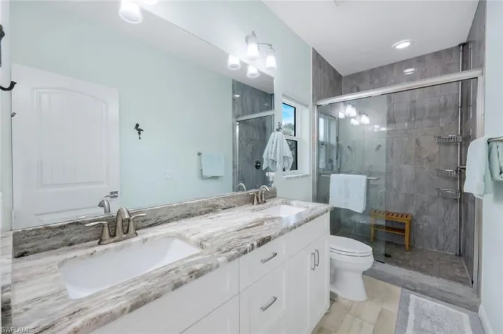 Full bathroom featuring double vanity and a stall shower