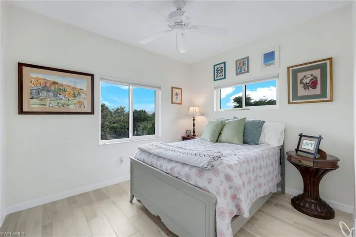 Bedroom featuring wood tiled floors, multiple windows, and ceiling fan