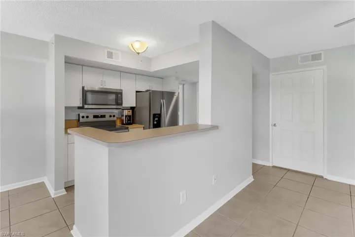 Kitchen featuring white cabinets, appliances with stainless steel finishes, a textured ceiling, and kitchen peninsula