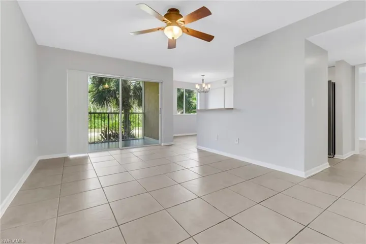 Tiled spare room featuring ceiling fan with notable chandelier