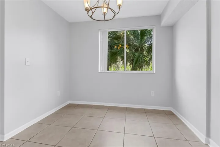 Tiled empty room featuring an inviting chandelier