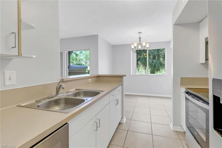Kitchen with white cabinetry, sink, a notable chandelier, decorative light fixtures, and appliances with stainless steel finishes