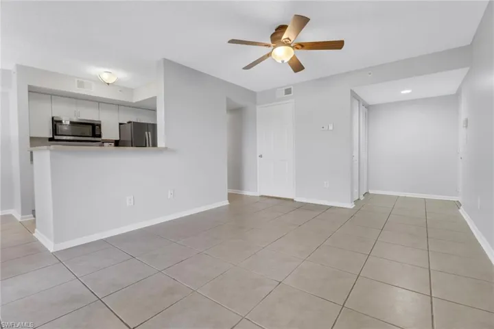 Unfurnished living room with ceiling fan and light tile patterned flooring