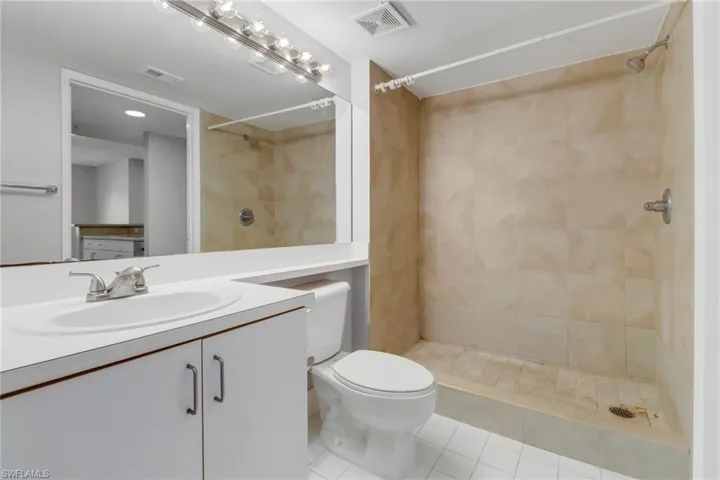 Bathroom featuring tile patterned floors, vanity, a tile shower, and toilet