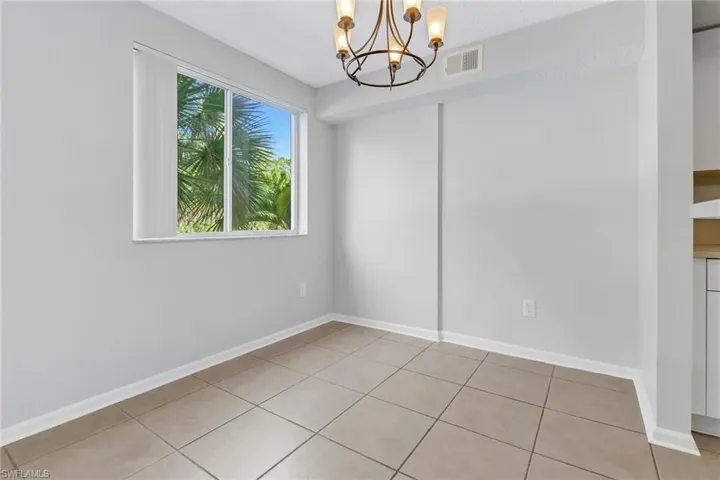 Tiled spare room with an inviting chandelier