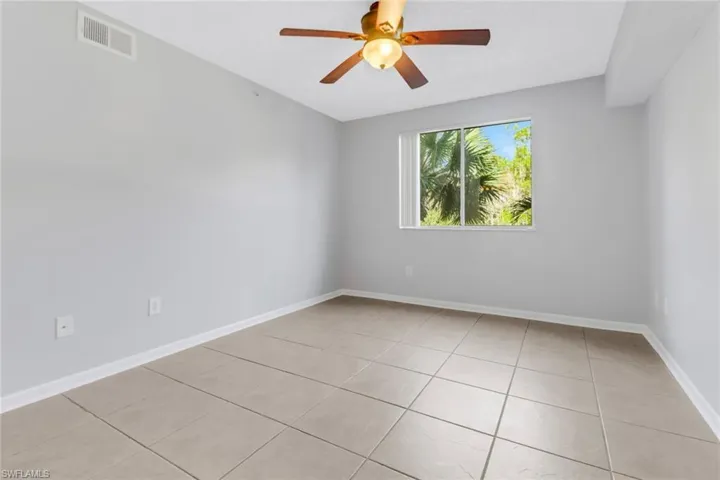 Empty room with ceiling fan and light tile patterned flooring