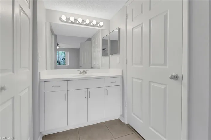 Bathroom with tile patterned floors, ceiling fan, vanity, and a textured ceiling
