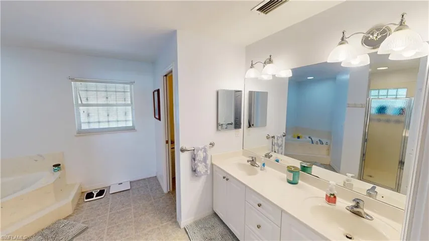 Bathroom featuring tile patterned floors, vanity, and plus walk in shower