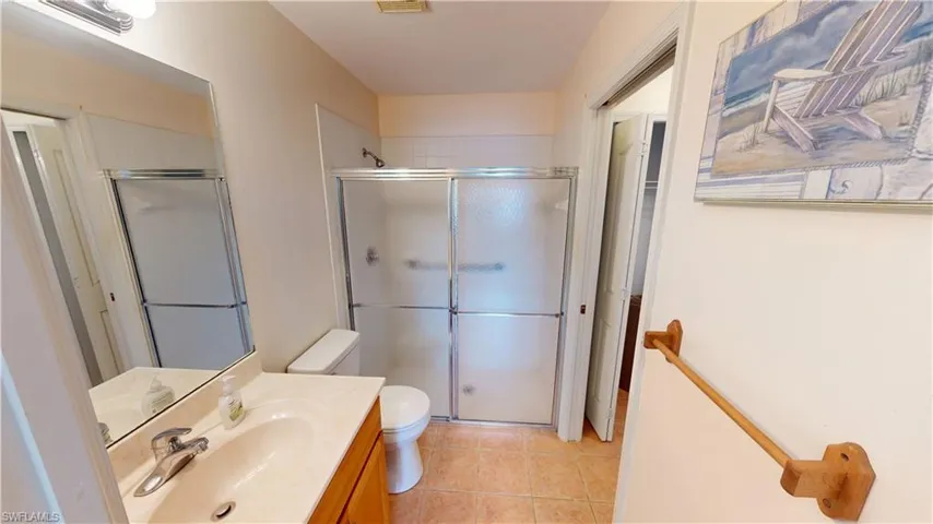 Bathroom with vanity, toilet, an enclosed shower, and tile patterned flooring