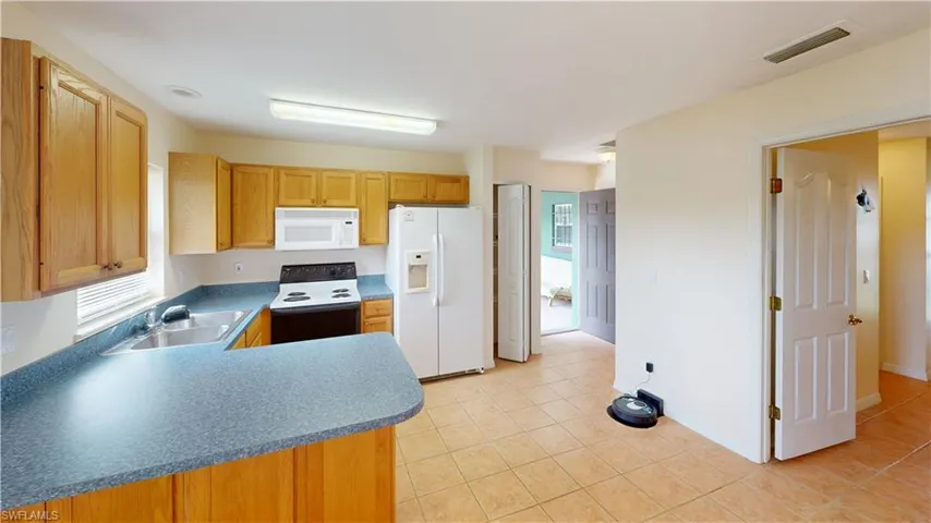 Kitchen with light tile patterned flooring, sink, and white appliances