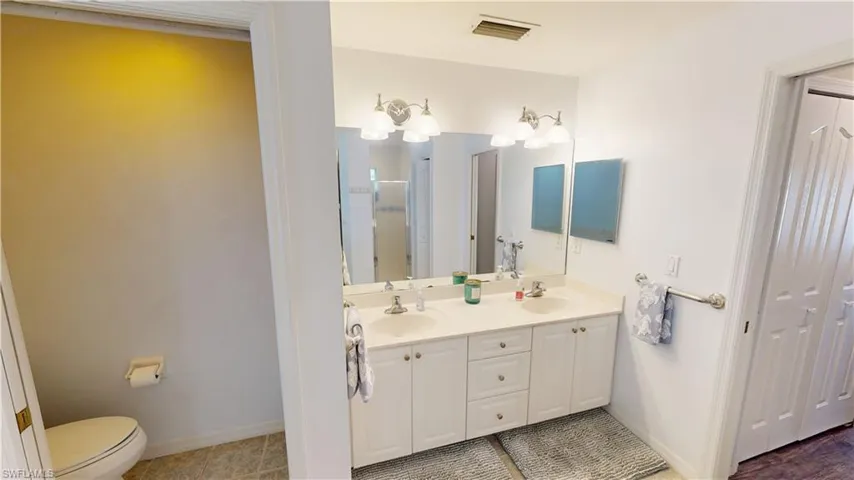 Bathroom featuring walk in shower, tile patterned floors, vanity, and toilet