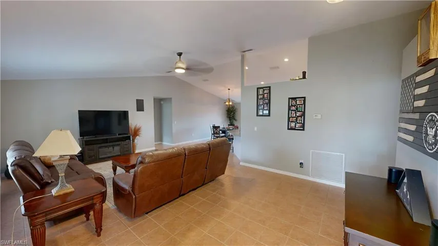 Living room featuring lofted ceiling, light tile patterned floors, and ceiling fan