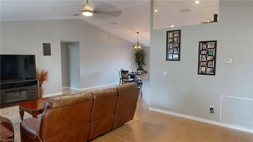 Living room featuring lofted ceiling, light tile patterned floors, and ceiling fan