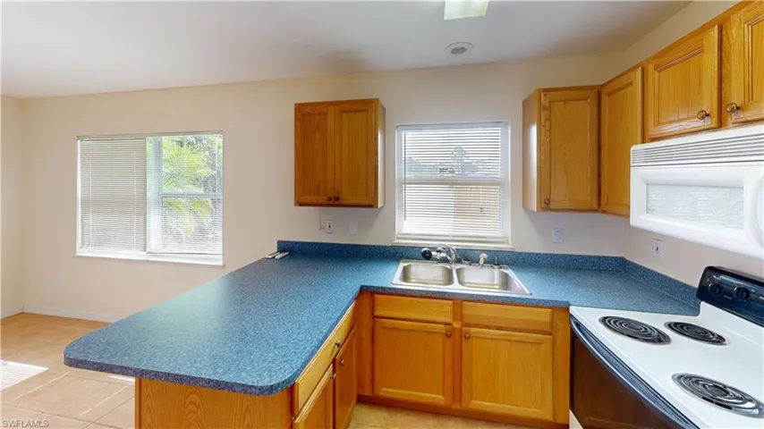 Kitchen with range with electric cooktop, sink, light tile patterned flooring, and kitchen peninsula
