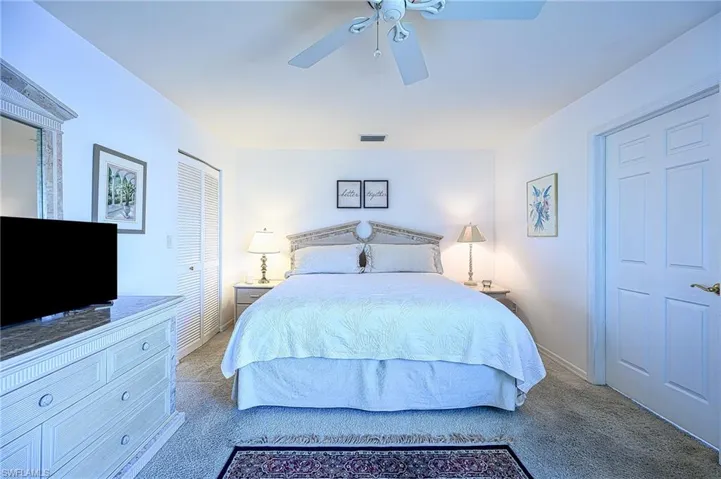 Carpeted bedroom with a ceiling fan and a closet