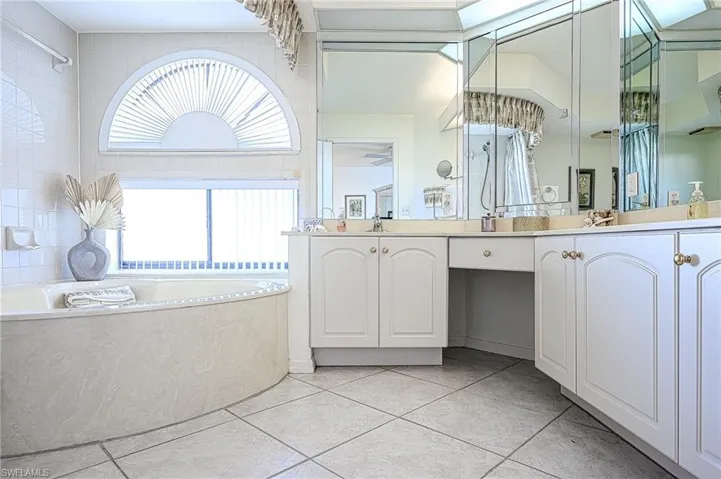 Full bathroom featuring a garden tub, double vanity, and tile patterned flooring