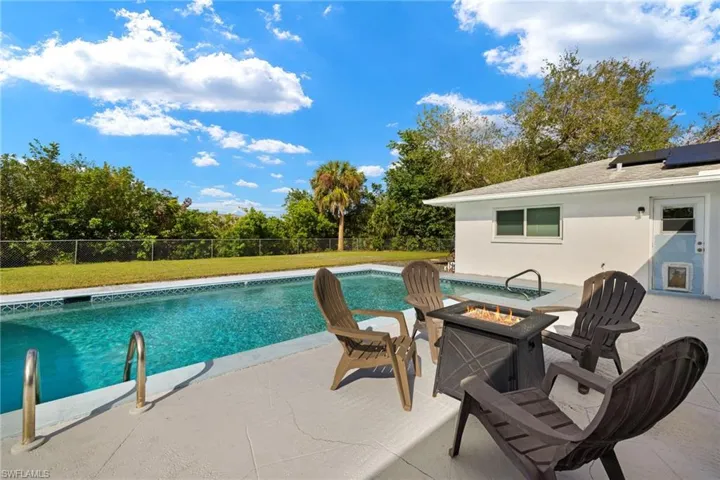 View of swimming pool featuring a fire pit, a patio area, and a lawn