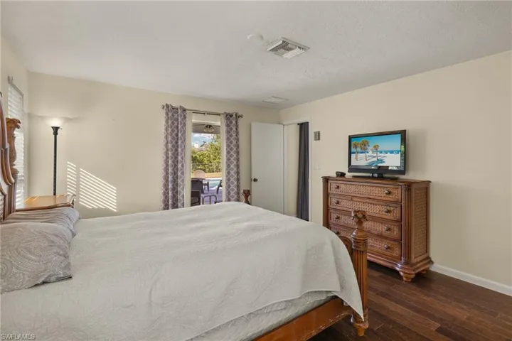 Bedroom featuring access to exterior, dark wood-type flooring, and a textured ceiling