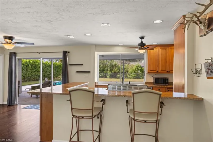 Kitchen with a breakfast bar area, light stone counters, a healthy amount of sunlight, and dark hardwood / wood-style floors