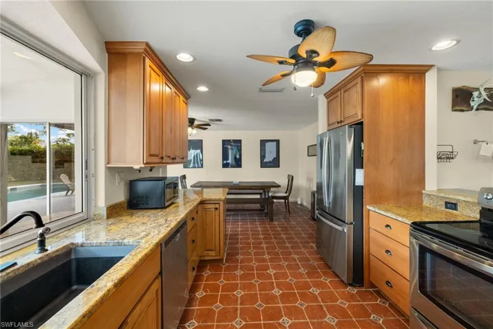Kitchen featuring ceiling fan, sink, light stone countertops, and stainless steel appliances