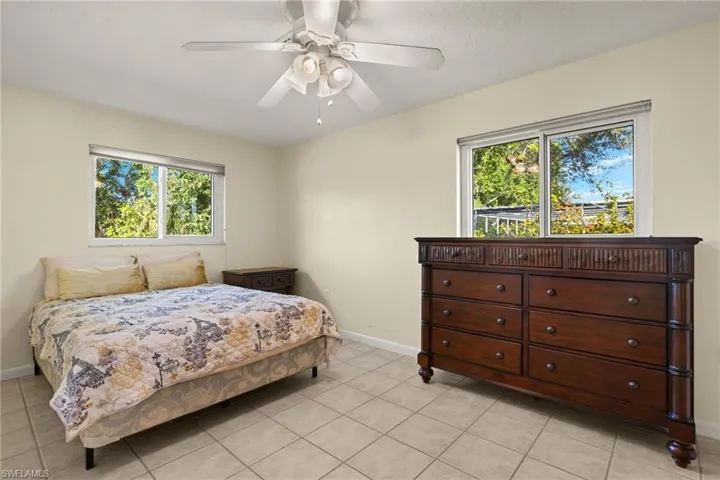 Bedroom with multiple windows, ceiling fan, and light tile patterned flooring