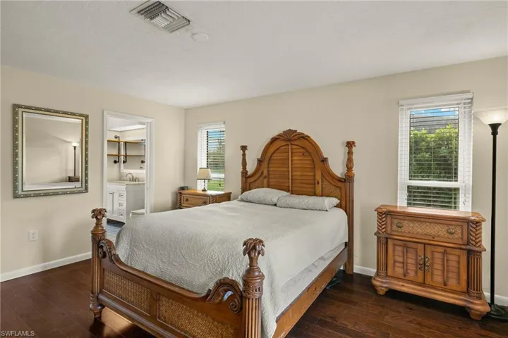 Bedroom featuring ensuite bath, multiple windows, dark wood-type flooring, and sink
