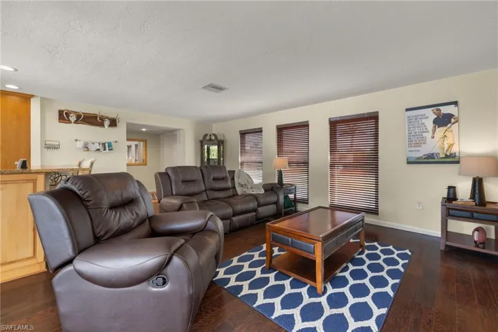 Living room with a textured ceiling and dark hardwood / wood-style flooring